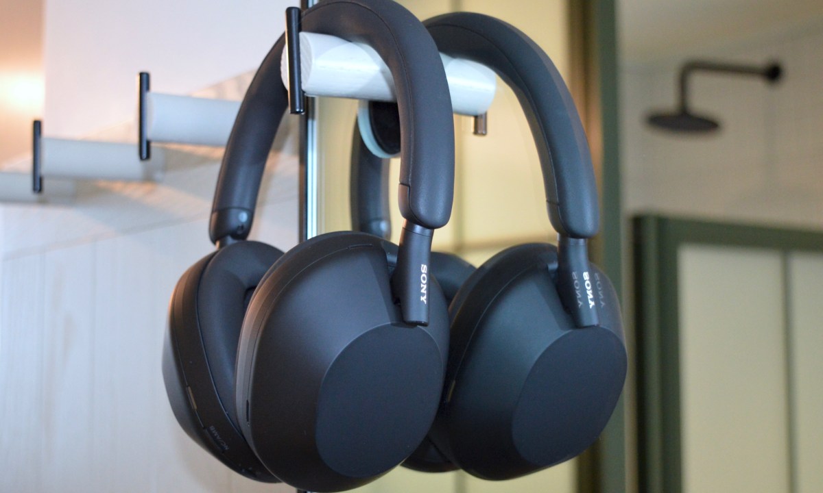 Sony WH-1000XM5 wireless headphones hanging on wall hook in front of a mirror.